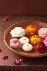 ranunculus flowers and candles in bowl for spa