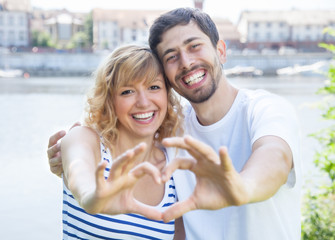 Couple in love outside showing heart with fingers