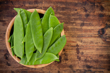 young pods of green peas on a wooden background