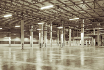 Concrete floor inside industrial building. Use as large factory, warehouse, storehouse, hangar or plant. Modern interior with metal wall and steel structure with empty space for industry background. © DifferR