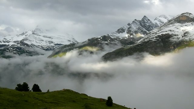 Silhouettes of high Alpine mountain sticking out from heavy mist