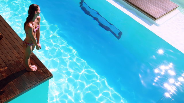 Brunette diving into clear blue pool