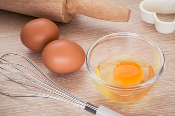 Fresh egg in bowl and metal whisk