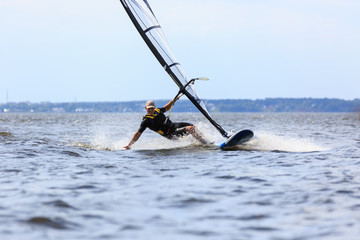 Young man surfing the wind in splashes of water