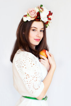 Portrait of beautiful girl with flower wreath holding apple
