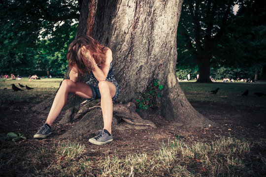 Depressed woman sittng under a tree