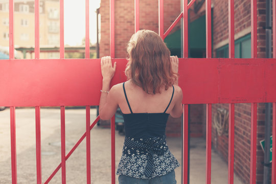 Young woman standing by a gate outside