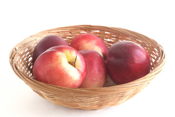 nectarines in a wicker basket isolated white background