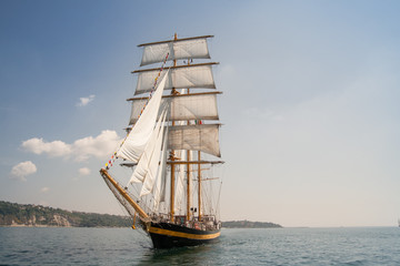 Vieux bateau avec des ventes blanches, naviguant dans la mer
