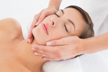 Attractive young woman receiving facial massage at spa center