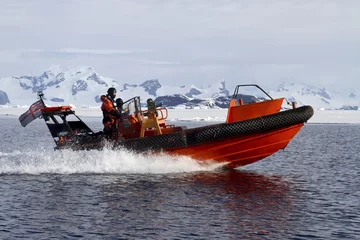 Foto op Plexiglas anti-reflex orange boat sailing at high speed in Antarctic waters against mo © Tarpan