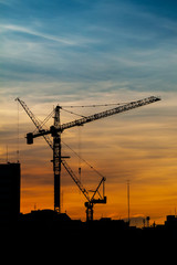 Silhouettes of construction crane in the colorful sky