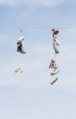 Old worn boots or shoes hang on a cable