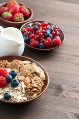 oatmeal and muesli in a bowl, fresh berries and jug of milk