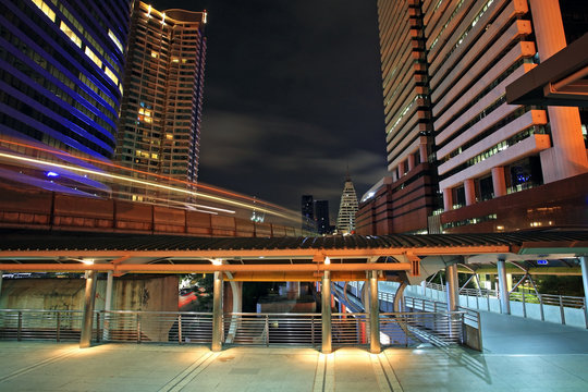 Light trails of Skytrain against modern buildings in Bangkok