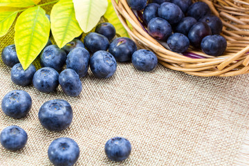 Blueberries in basket with leaves on linen cloth