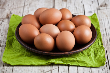 fresh brown eggs in plate and green napkin
