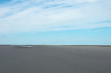 Fototapeta na wymiar Picture of an empty outstretched beach when its ebb with a blue sky on Schiermonnikoog in the Netherlands