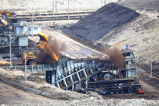 heavy construction tipper trucks dump coal to the conveyor at co