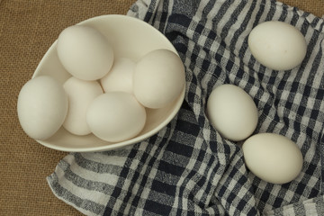 Eggs in a white bowl with napkin on table mat.