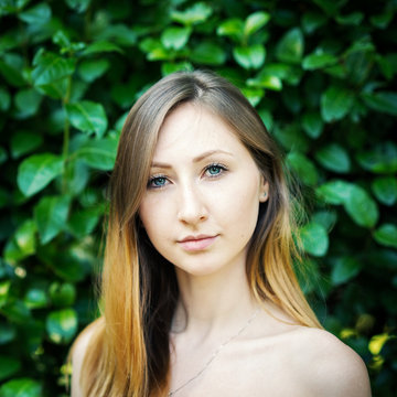 Close up portrait of young woman with natural green hedge backgr
