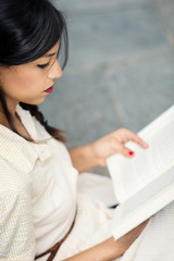 Beautiful brunette woman reading a book outdoors.