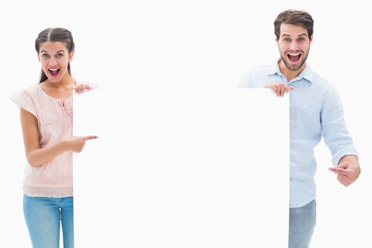 Attractive Young Couple Smiling At Camera Holding Poster