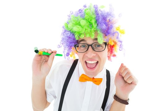Geeky hipster wearing a rainbow wig holding party horn
