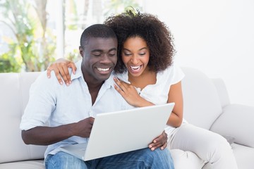 Attractive couple using laptop together on sofa