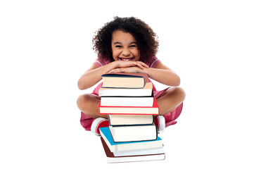 Cute school girl leaning over stack of books