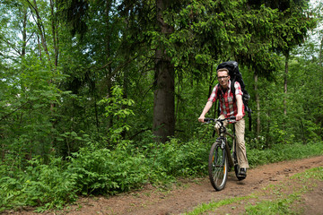 Naklejka premium Man riding a bike in the forest road