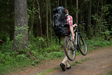 Fototapeta na wymiar Man carrys his bike on wood path