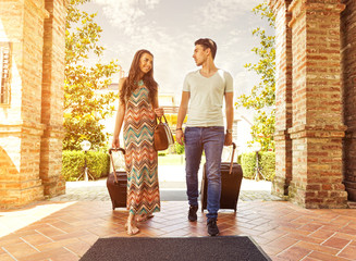 Young couple standing at hotel corridor upon arrival - obrazy, fototapety, plakaty