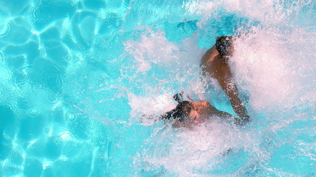 Couple holding hands and jumping in the swimming pool
