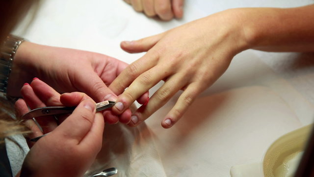 Nail technician removing cuticles from customers nails