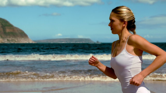 Fit blonde jogging on the beach