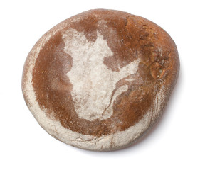 A loaf of fresh bread covered with rye flour in the shape of Que