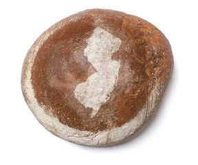 A loaf of fresh bread covered with rye flour in the shape of New