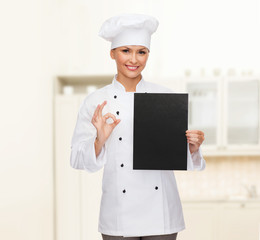 smiling female chef with black blank paper