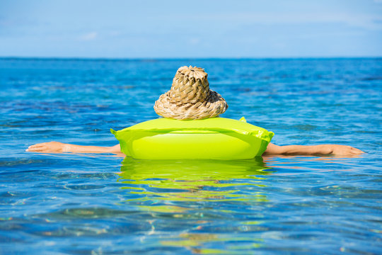 Woman Floating On Raft In Tropical Ocean