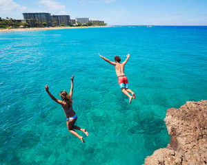 Friends cliff jumping into the ocean