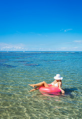 Woman floating on raft in tropical ocean