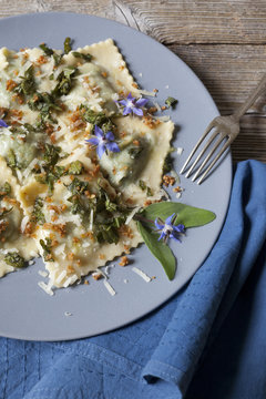 handmade pasta ravioli with borage, flowers and sage on plate
