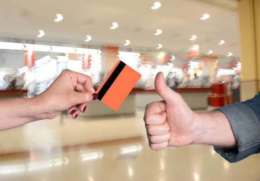 Woman holding credit card, man gesturing thumb up