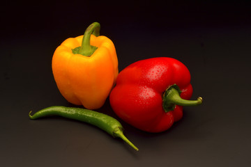 Sweet and chilli pepper on black background
