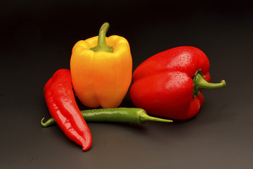 Sweet and chilli pepper on black background