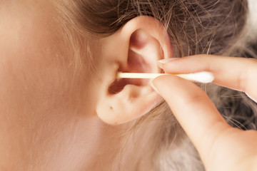 woman cleans her ear using cotton swab