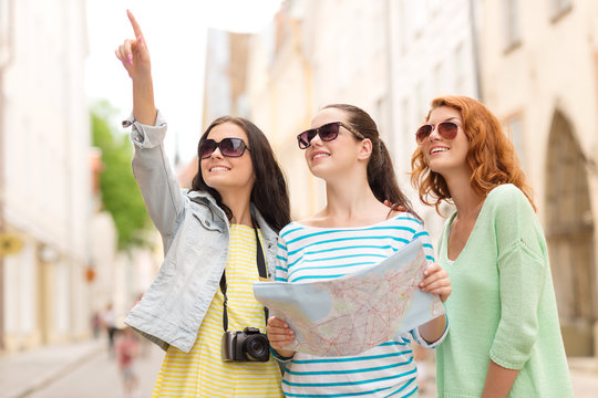 smiling teenage girls with map and camera