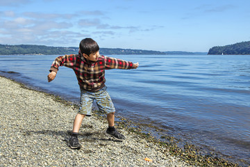 Boy skips a rock in the water.