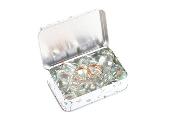 Two wedding rings on a transparent glass beads in a metal box is